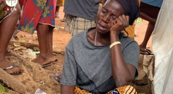 Nigérijská žena sedí na zemi a plače po krvavom útoku pastierov z kmeňa Fulbov.